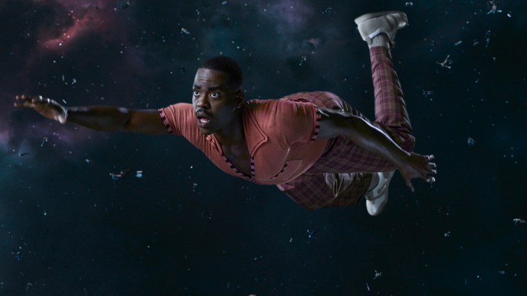 Ncuti Gatwa as the Fifteenth Doctor in tartan trousers and an orange top and floating in space