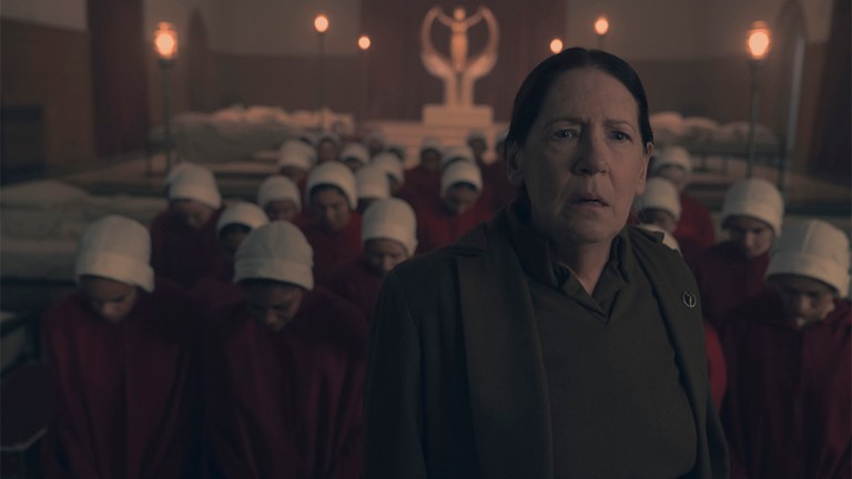 Ann Dowd looking serious backed by Handmaids and a Gilead statue in The Handmaid's Tale season six episode eight