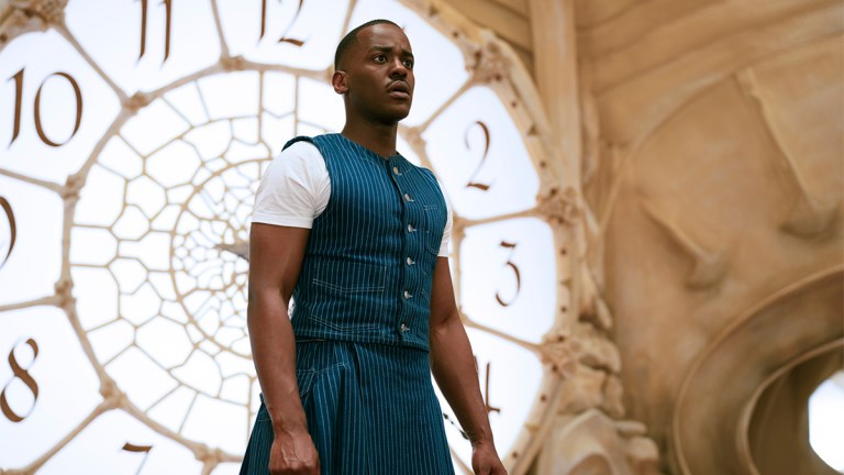 Ncuti Gatwa in a blue and white outfit standing in front of a clock in Doctor Who