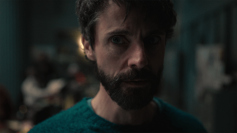 Matthew Goode with a beard, wearing a green jumper and looking worried in Netflix's Dept. Q